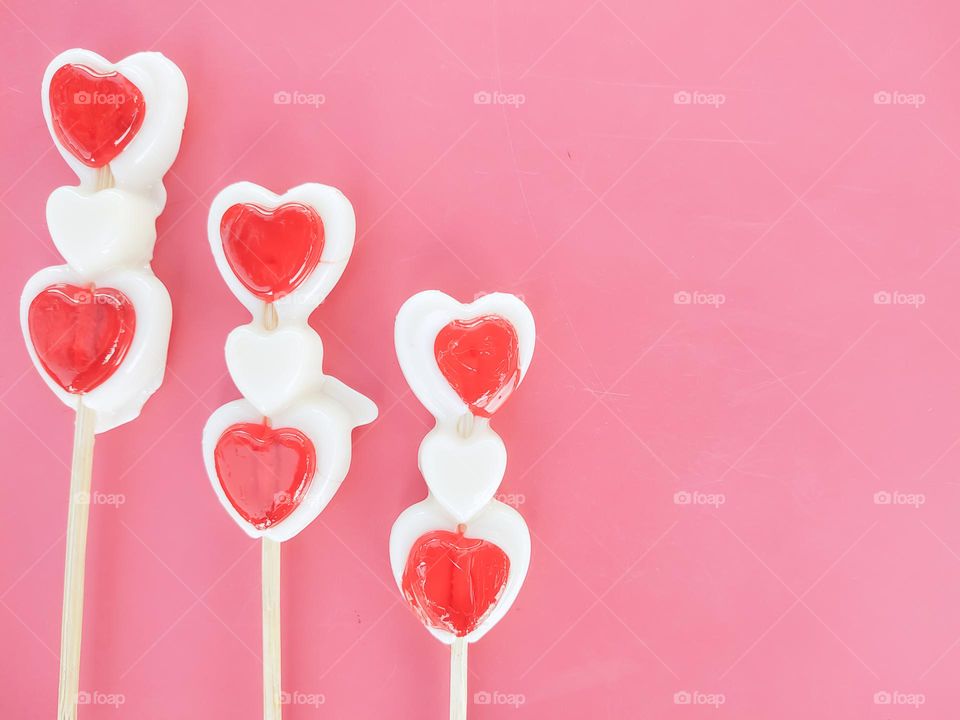 Valentine's day background with three red and white Lollipop Candy on pink pastel background