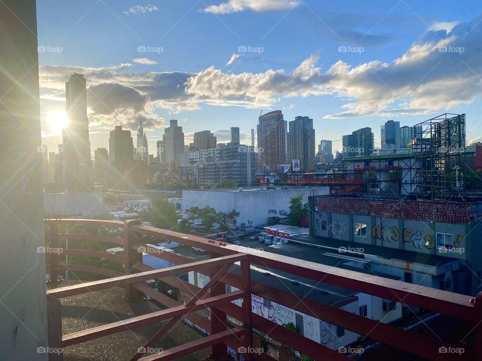 The “East River”, “Long Island City” and in the far distance “Manhattan” can be seen here from the “Pulaski Bridge”. The setting sun bathes this metropolitan cityscape in a beautiful warm golden light. 2023. Hypnotic Productions