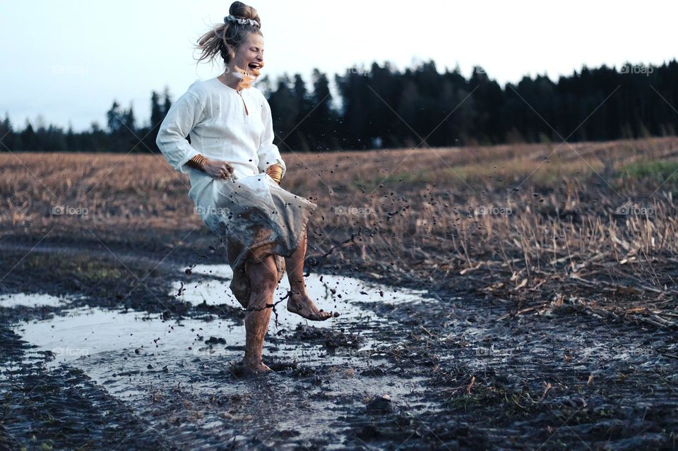 Crazy and happy woman dancing in the autumn mud on field