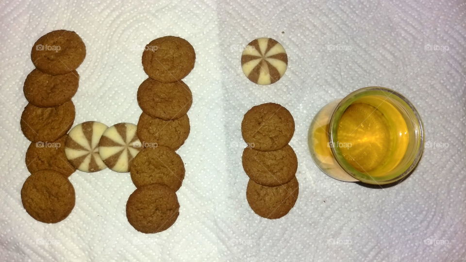 Cookies that spell out the word, "hi" and a cup of green tea.