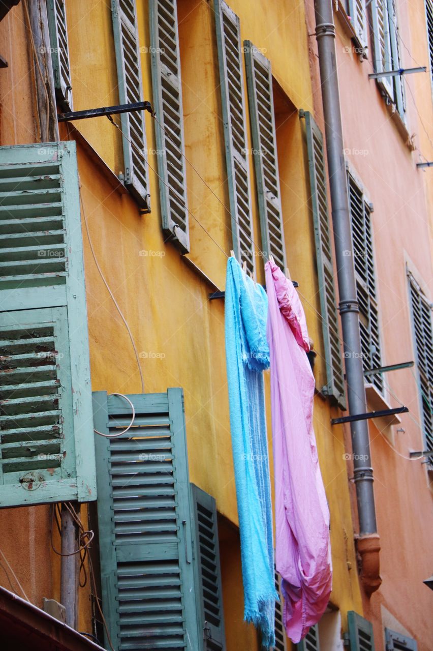 Colourful sheets hanging of an open window of an old colourful building 