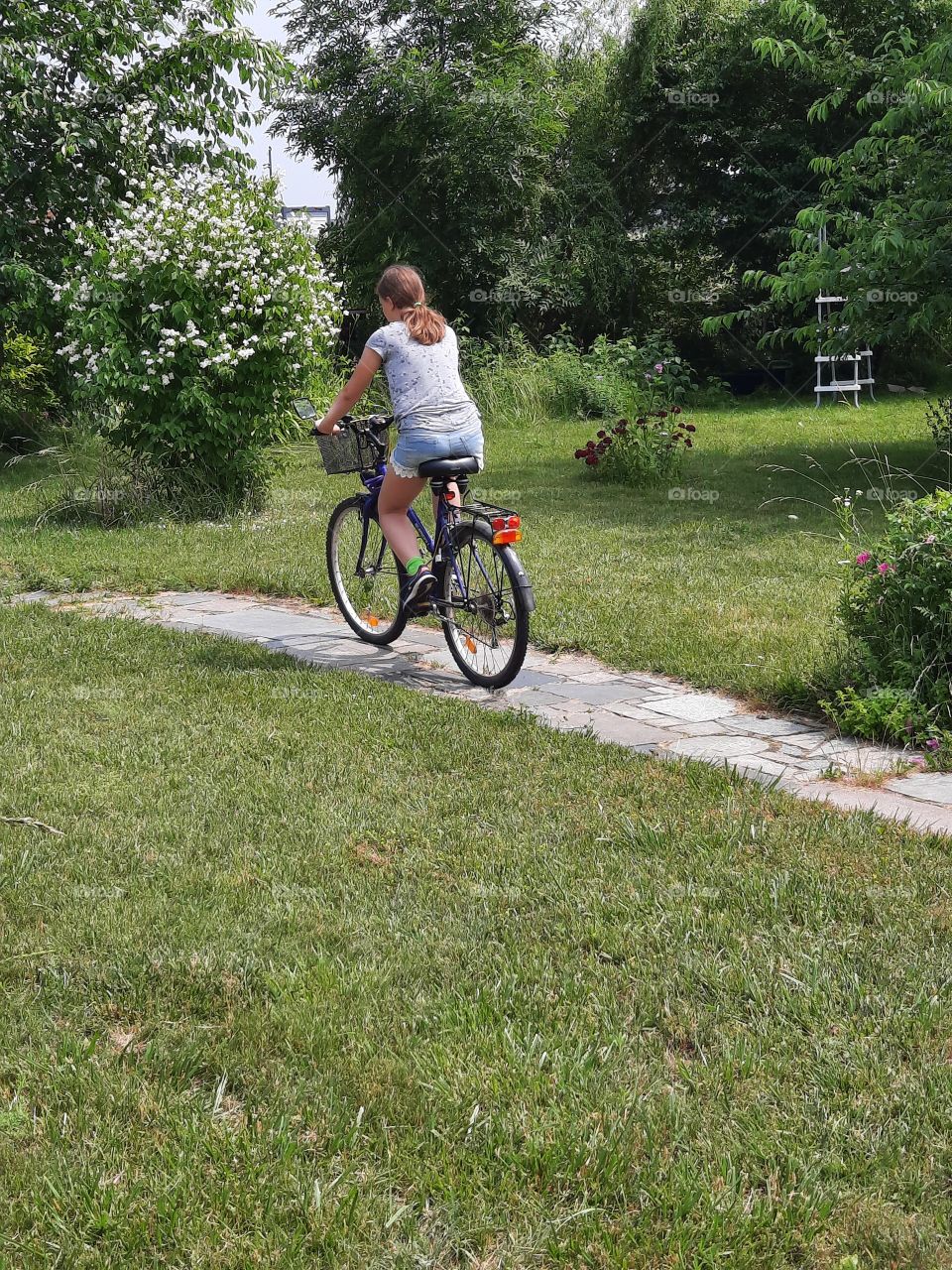 girl riding bike in the garden on a hot summer day