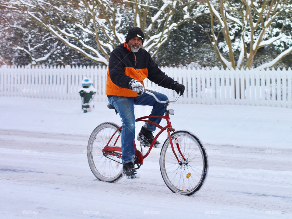 A man rides his bicycle on a snow plowed road after a snow storm on the Eastern Shore of Maryland in Easton
