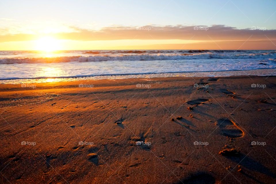 footsteps in the sand during sunset on beach