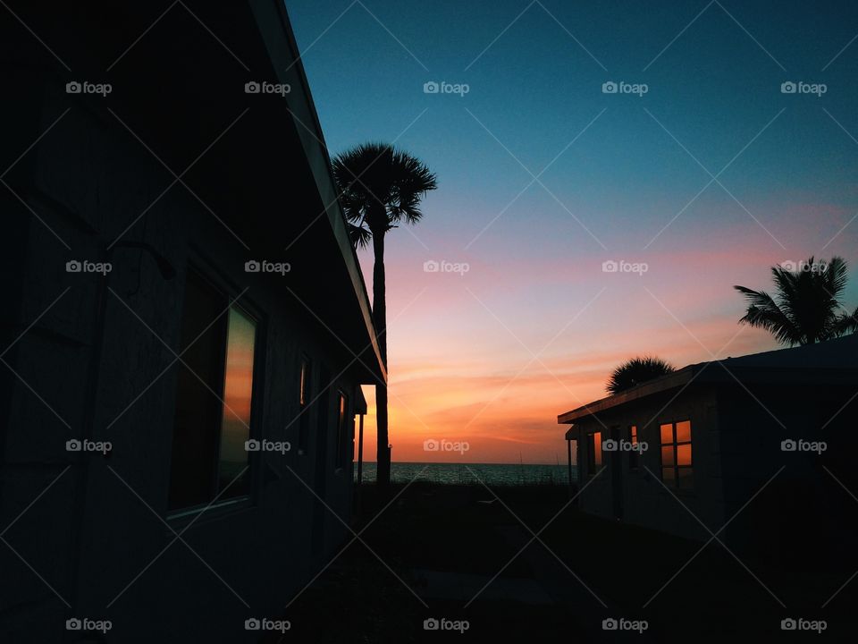 Classic old Florida beach houses at sunset with palm trees in background. Florida vacation homes with a beautiful sunset in background
