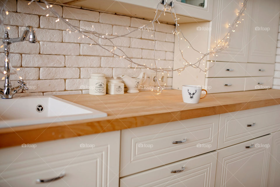 Festive winter cozy kitchen interior with garlands, decorations and gifts.  Christmas dinner at the decorated table.