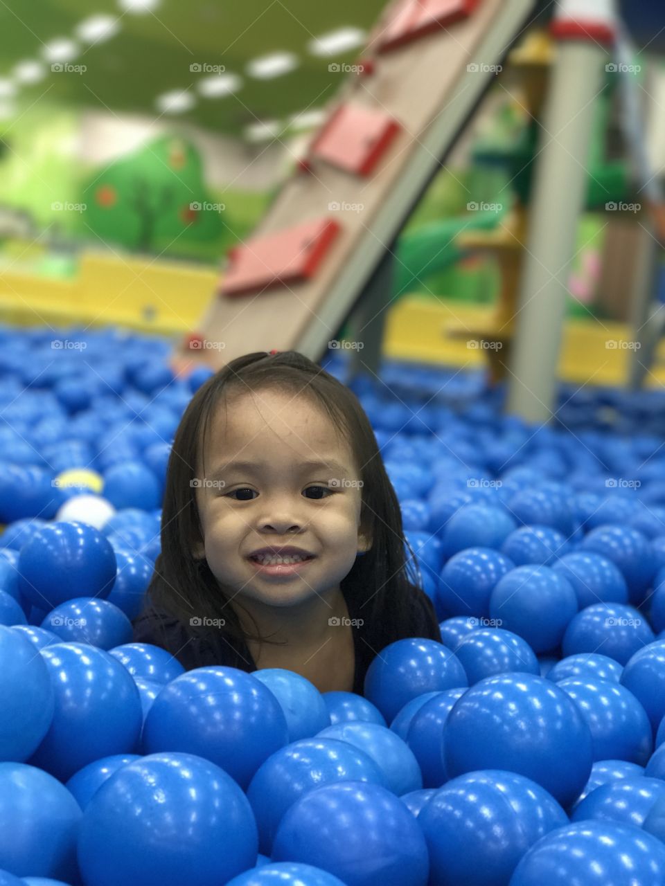 Asian girl surrounded with blue plastic ball