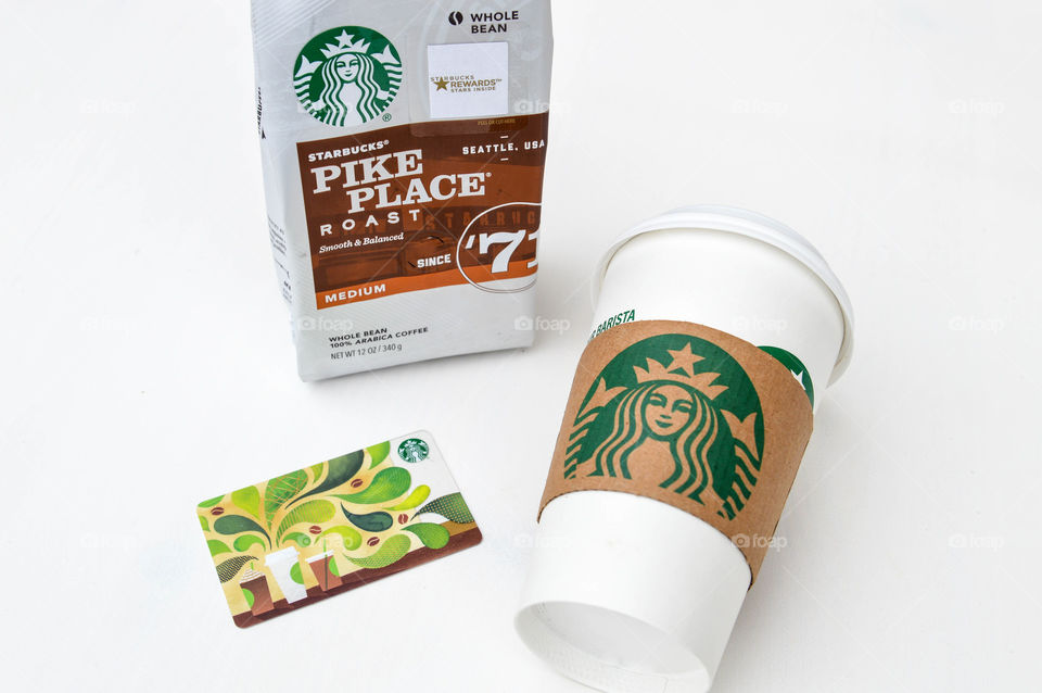 Starbucks coffee cup laid out on a white table with a Starbucks bag of coffee and a Starbucks card