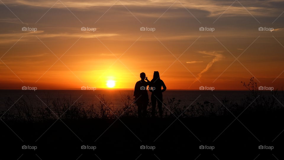 Two friends standing near the ocean soaking the last rays of the day.