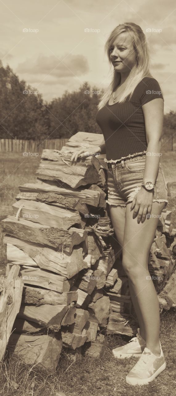 Woman standing near the stack of log