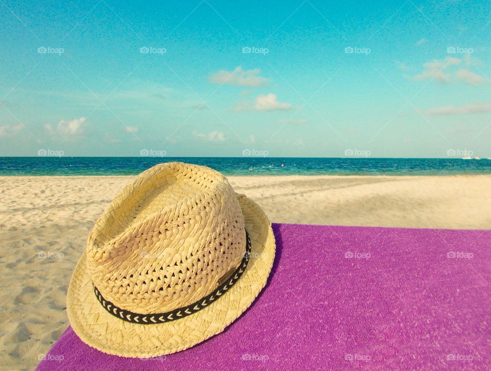 Straw hat on the sunny beach. Summer vacation 