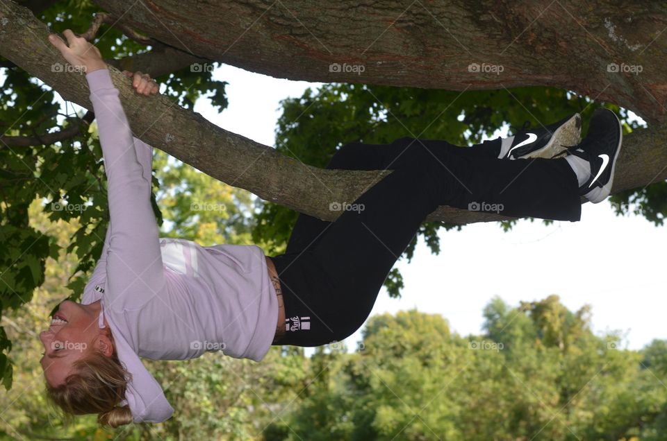 Happy woman hanging on tree branch