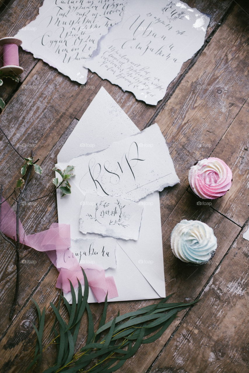 Graphic arts of beautiful wedding calligraphy cards with two mini cakes and pink chiffon ribbon on wood background.