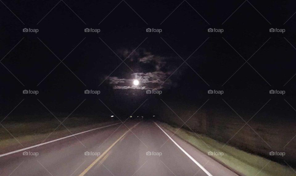 moon through clouds over road