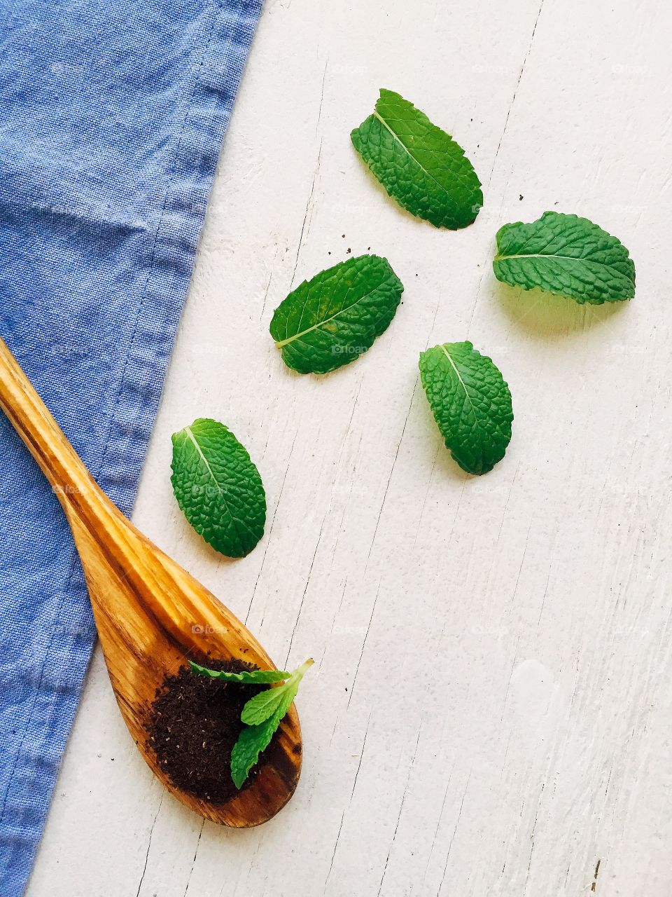 Dried tea leaves on wooden spoon with mint leaves