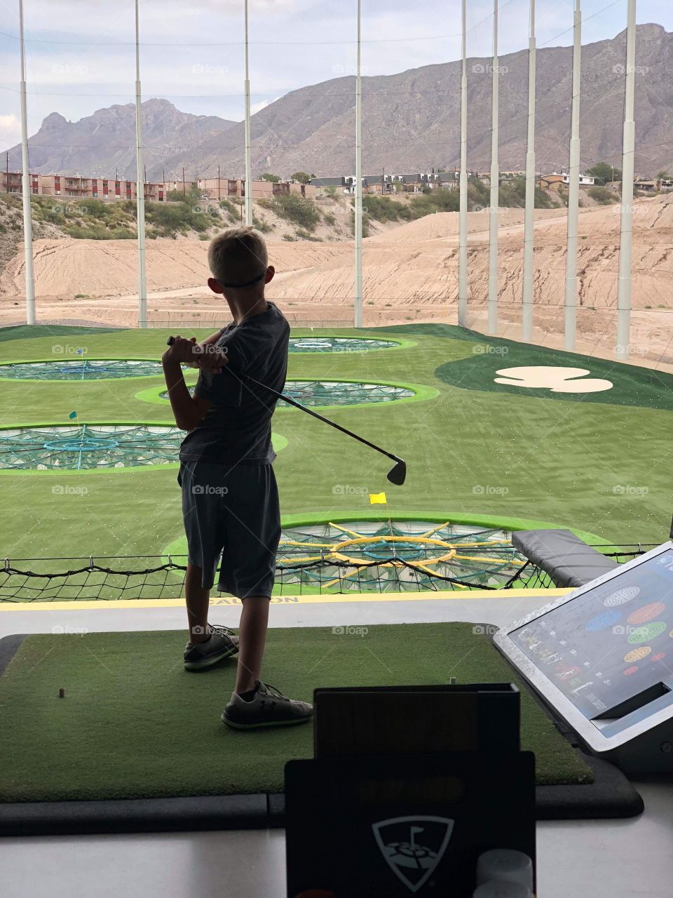 Young boy learning to play golf outdoor range