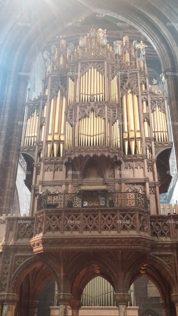 Ancient cathedral organ in Bath, England towering over tourists as they glance at the stunning architecture and history.