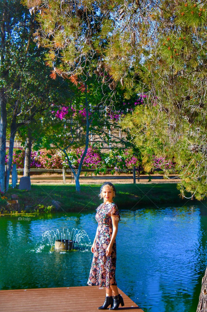 Smiling young woman standing near pond