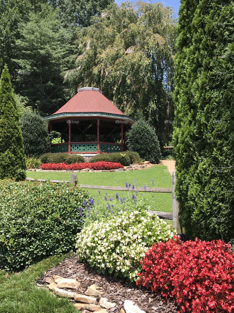 Gazebo in a beautiful lush green and floral garden park on a sunny summer day. 