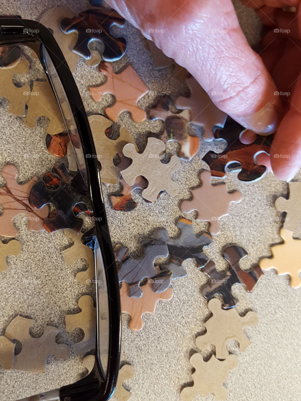 High angle view of person holding puzzle and eyeglass