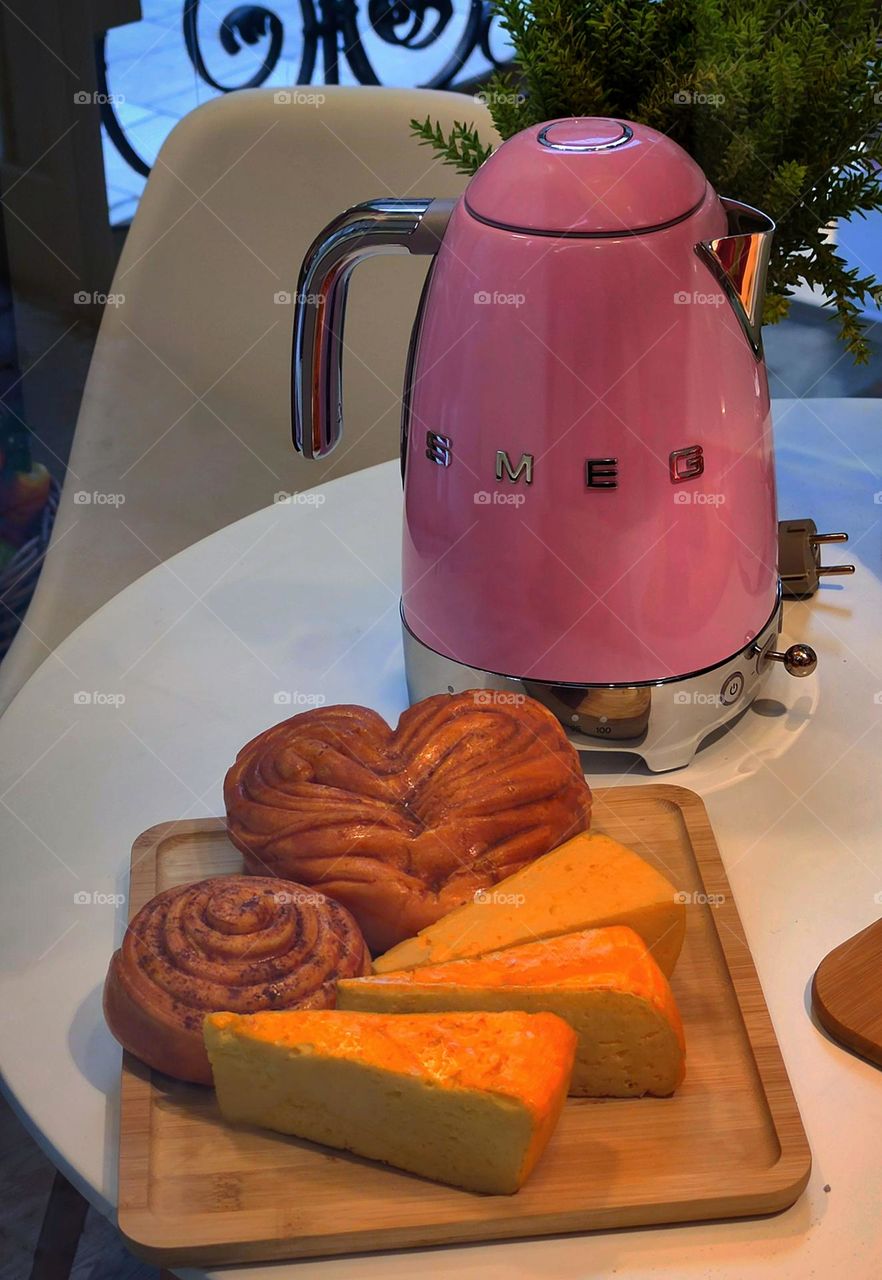 Kitchen table. Electric kettle and desserts: cottage cheese casserole, cinnamon bun and raisin bun