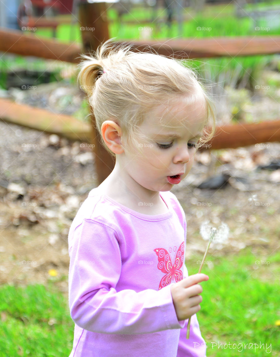 Close-up of blonde girl holding dandelion flower