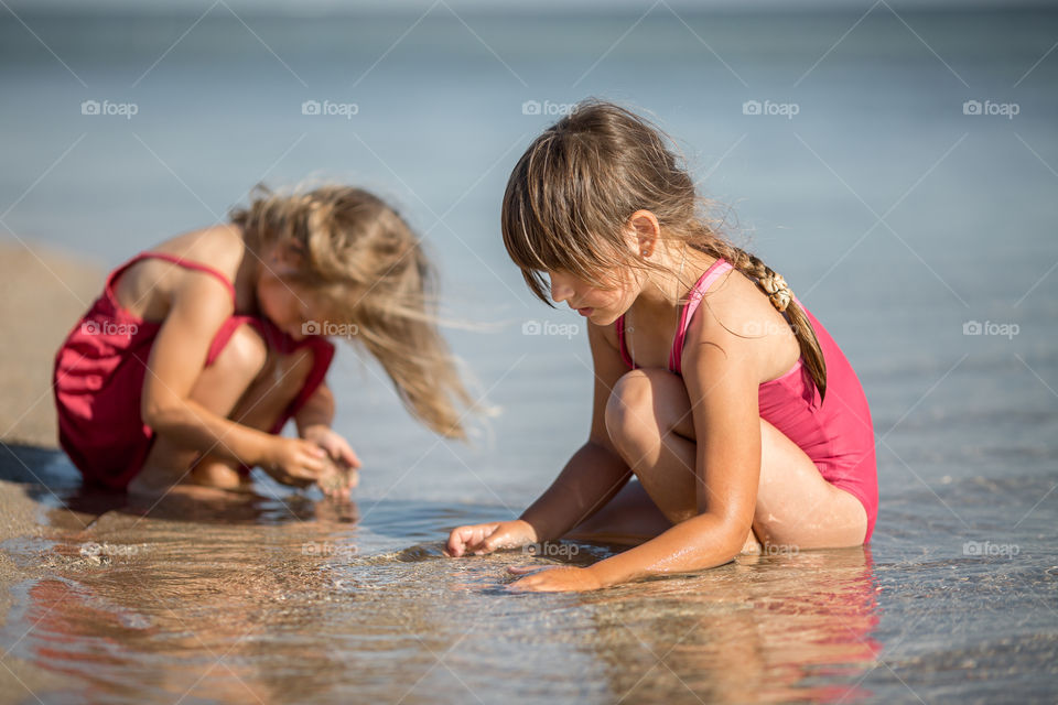 Little sisters playing in the sea