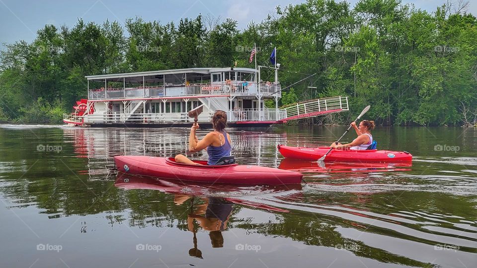 kayaking past river boat