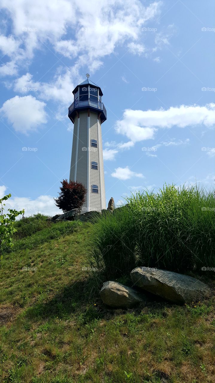 A lighthouse stands alone on a hillside.