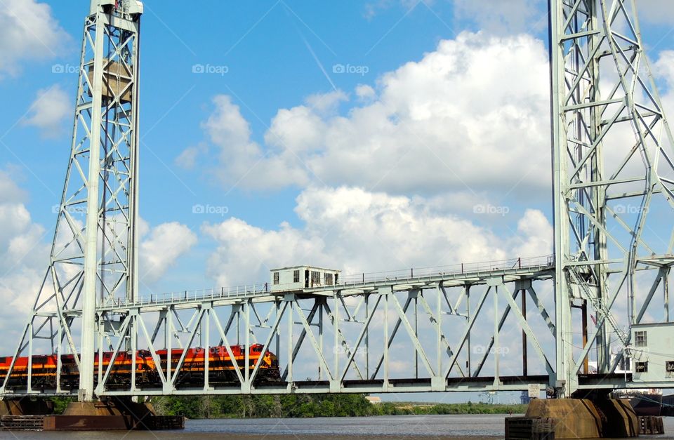 Train bridge . A train going one way on a suspension bridge over a river 