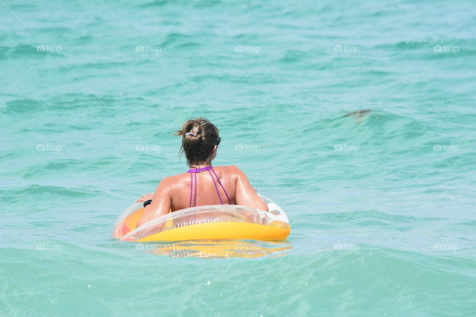 Young female adult floating in tropical water.