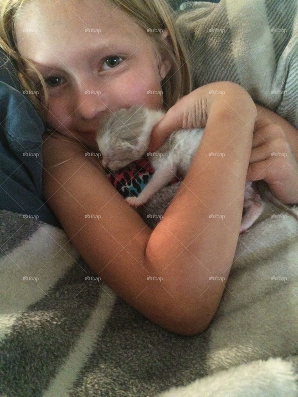 Child cuddling with newborn kitten