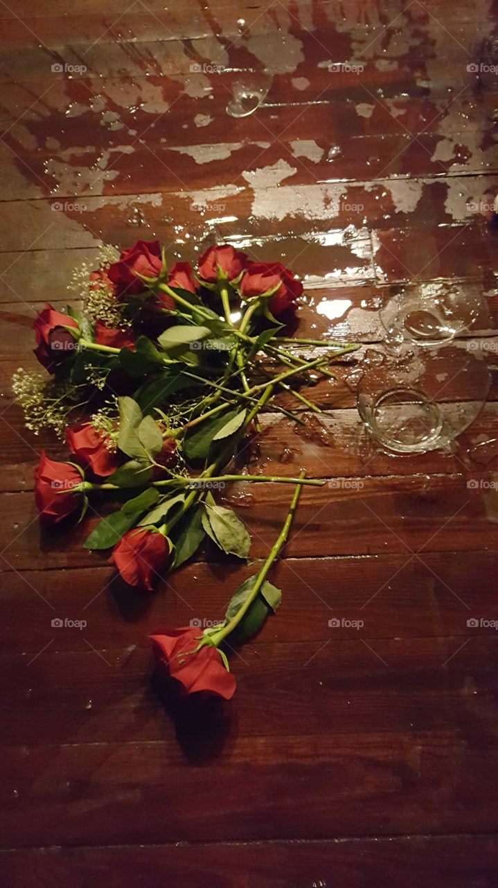 Red Roses in a glass vase crashed onto the wooden floor. Please don't cry over spilled roses ...