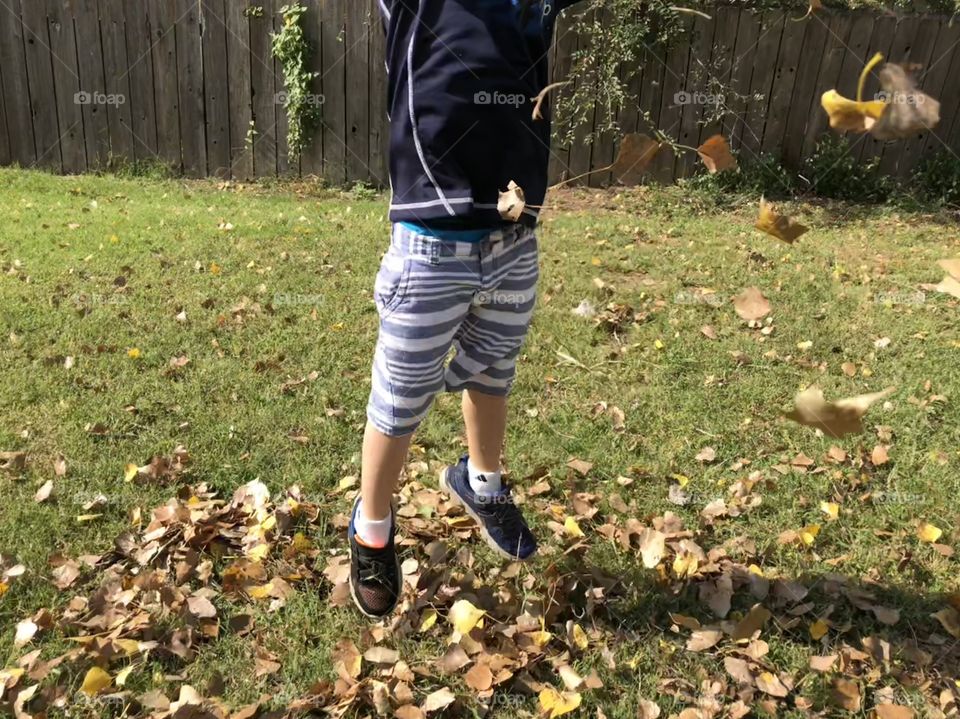 Boy jumps in leaves