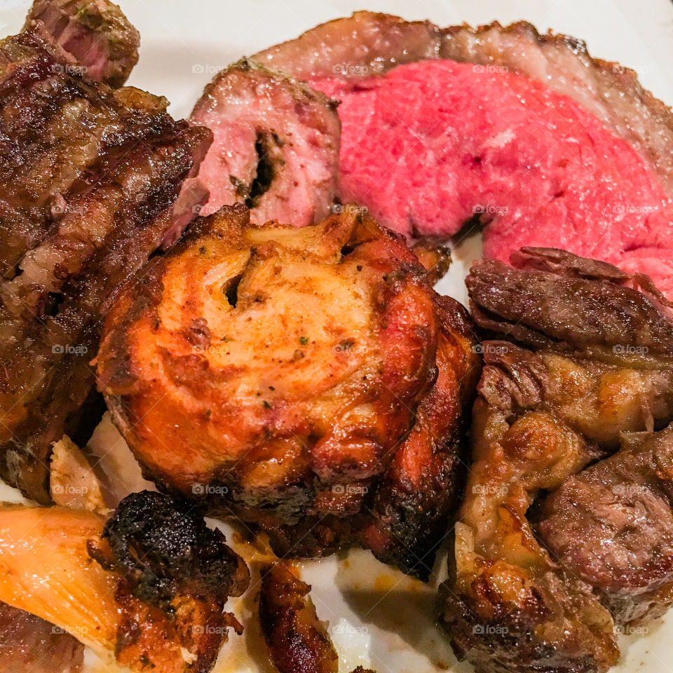 Square photo of a plate with a variety of roasted meats.
