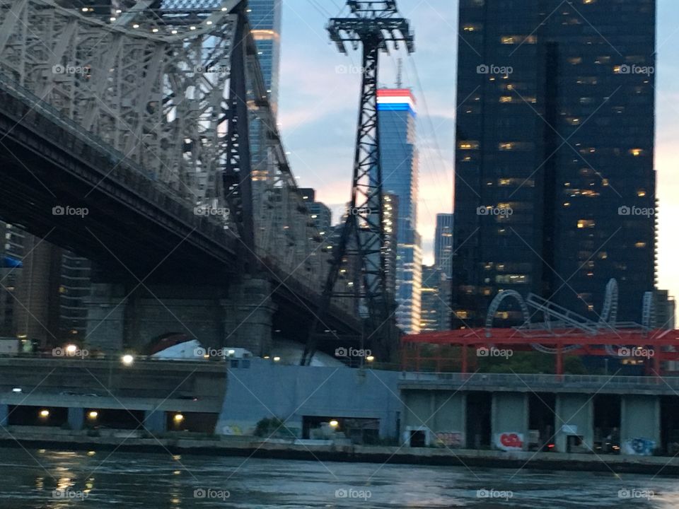 A twilight time view of Manhattan’s Upper East Side seen from aboard our sailboat „Salvation“ just about to pass underneath the Queensborough Bridge at 69th St traveling southbound towards LIC, Queens, NY. 2017. Hypnotic Productions