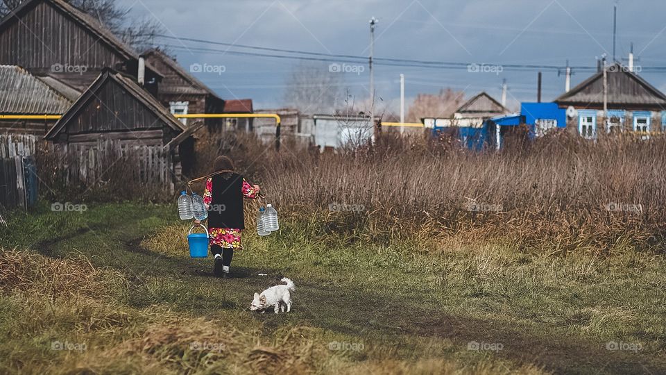 grandmother from a Russian village carries water in plastic bottles