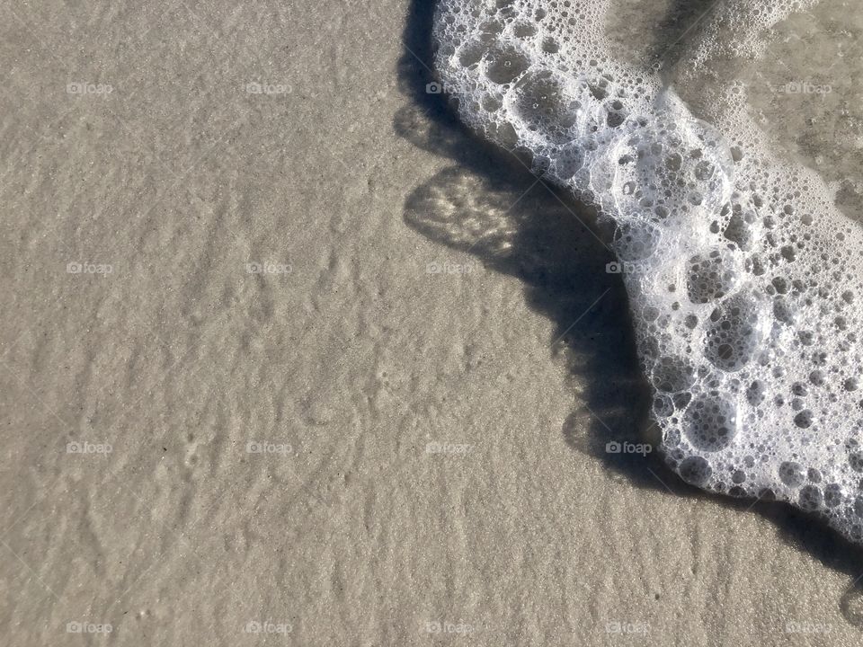 Shadow of bubbles and waves on smooth wet sand 