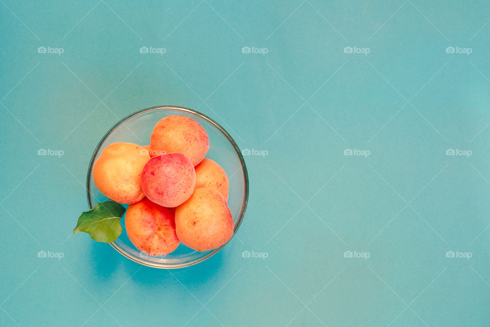 Apricots in a bowl on blue