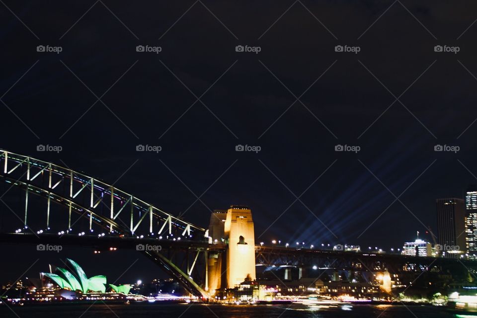 The Sydney harbour bridge and the Sydney opera house in the evening surrounded by the bright lights of vivid festival 