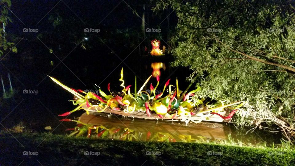blown glass art on canoe on a still lake at night creates a reflection