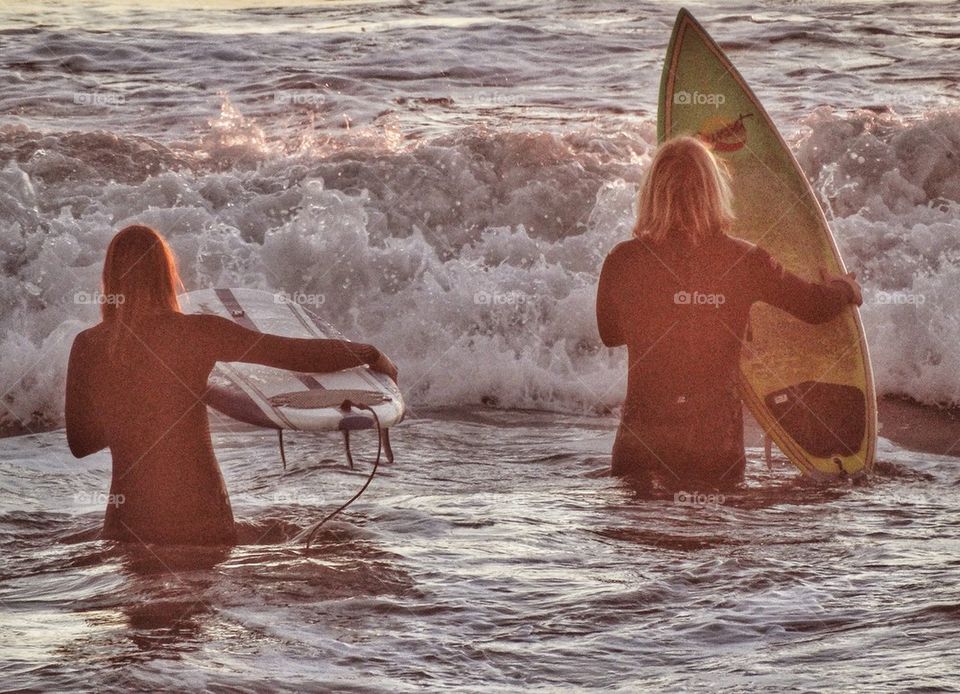 California Surfers Hitting The Waves At Sundown. Surfers In The Morning
