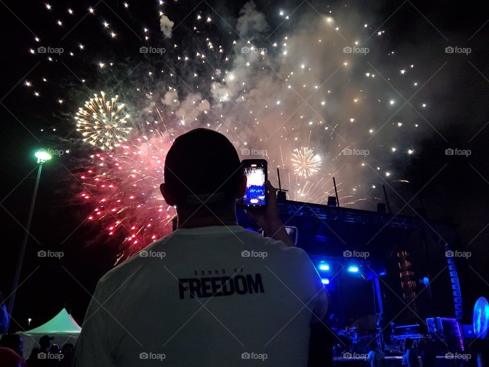 Silhouette of a man enjoying a nighttime Independence Day celebration with fireworks.