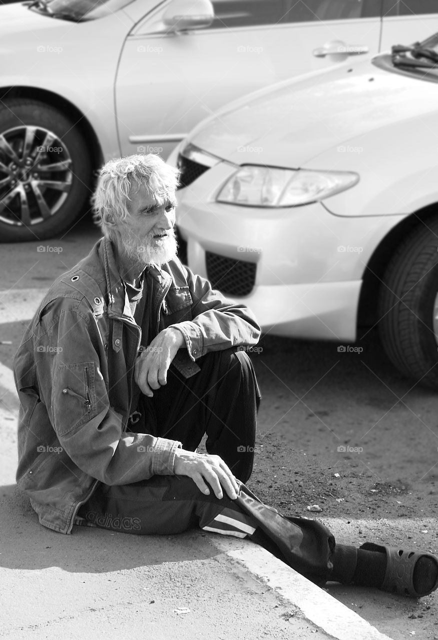 Homeless sad man sitting on street