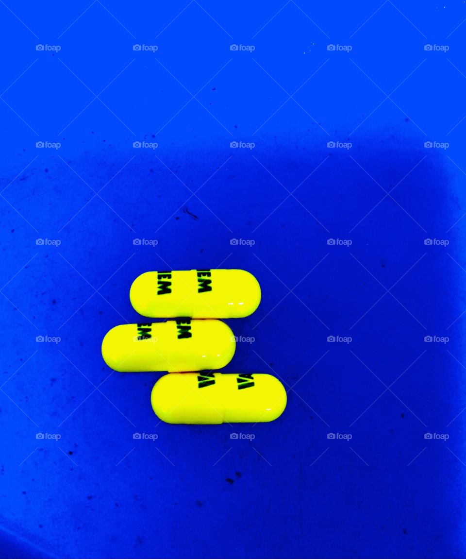 Three yellow capsules on a solid blue plate. 