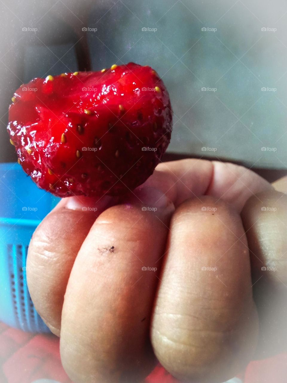 a child's hand holding a strawberry