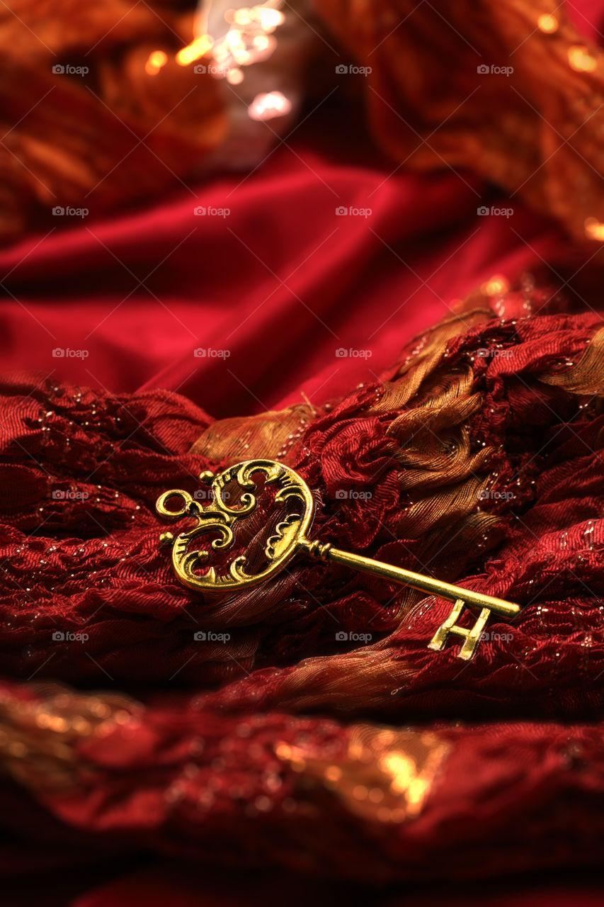 Antique golden key on red fabric background