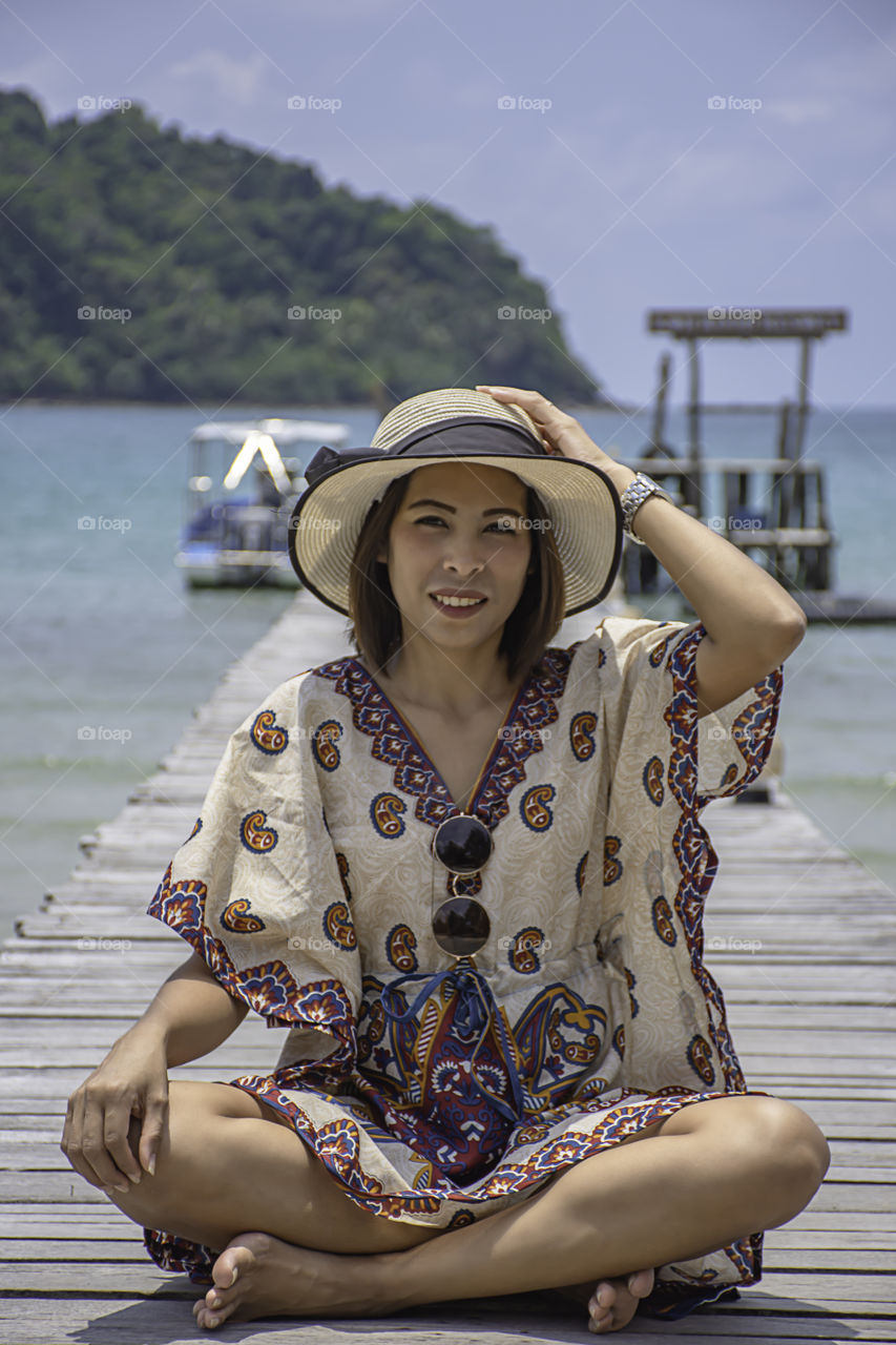 Women Wear a hat on the wooden bridge pier boat in the sea and the bright sky at Koh Kood, Trat in Thailand.