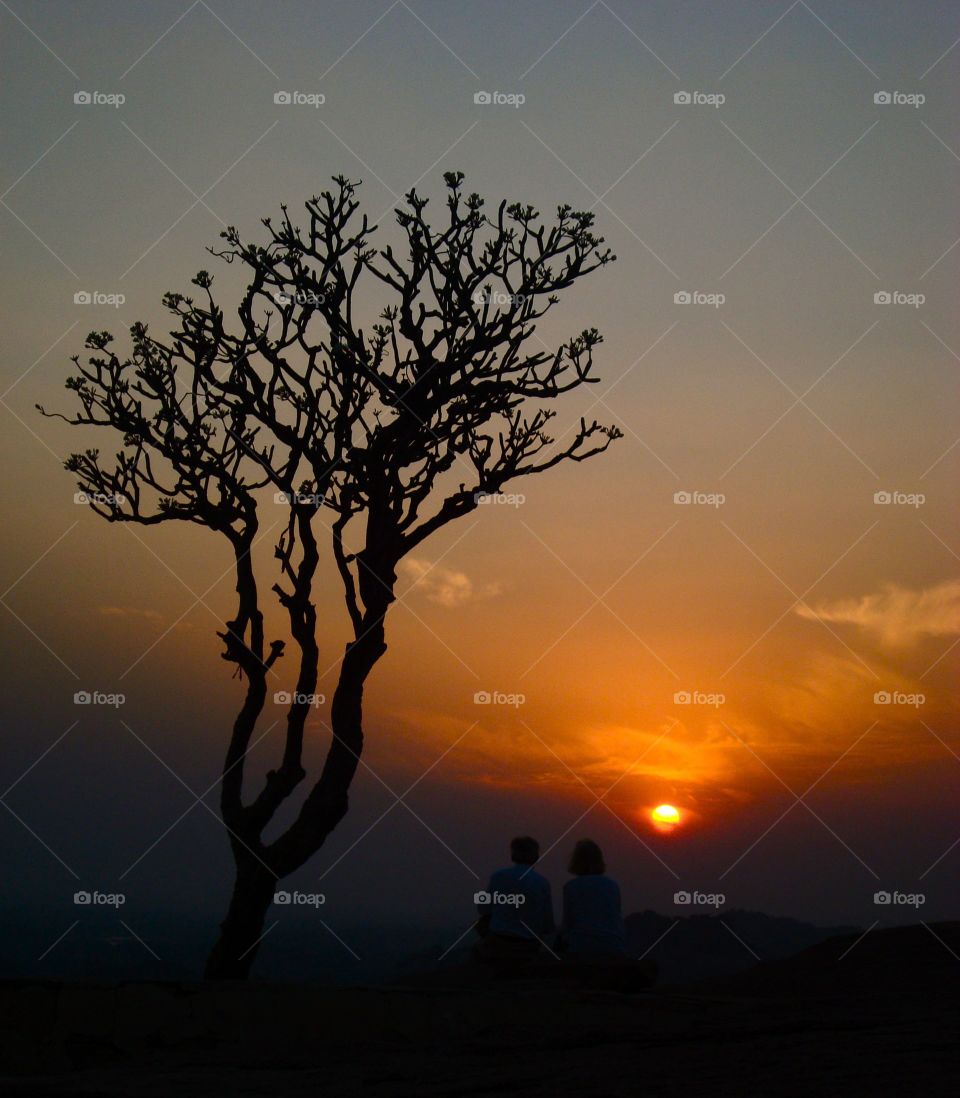 Silhouette of a couple sitting on mountain at the time of sunset