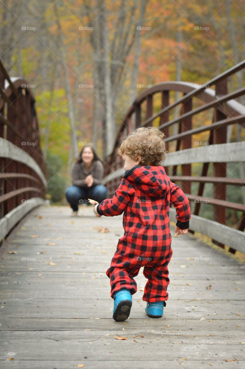 Mother and Son. One-year-old boy running to his mother on a bridge. Photo taken at Mills River in North Carolina.